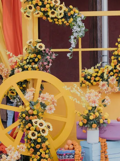 A decorative yellow cart adorned with sunflowers and oranges, adding a rustic and charming element to the Haldi decor.