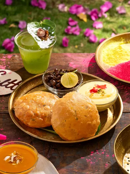 A platter of traditional Holi snacks and drinks, shot outdoors to capture the festive atmosphere.