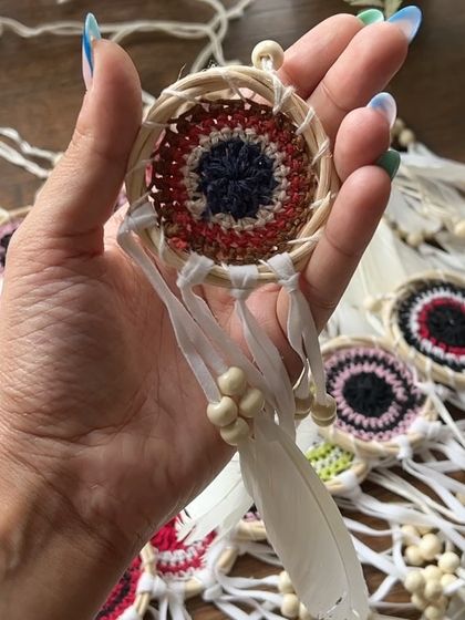 Another look at our evil eye dreamcatcher. The combination of natural cane, soft yarn, and feathers creates a beautiful, textured piece.