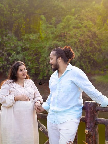 A candid moment of the couple sharing a look while holding hands. The warm, golden sunlight filtering through the trees adds a magical touch to this outdoor portrait.
