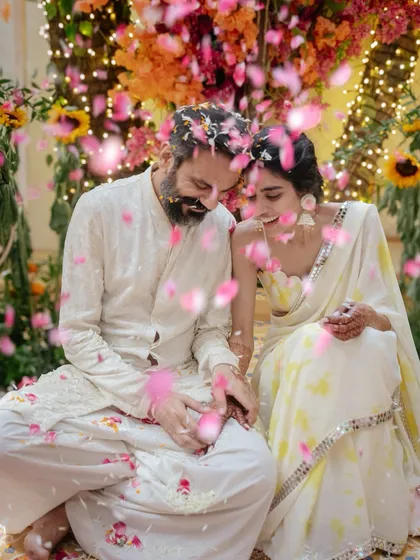 Nikki and Vishal are showered with pink and yellow petals during their haldi. This beautiful, colorful moment captures the love and joy surrounding them as they celebrate with their closest family.
