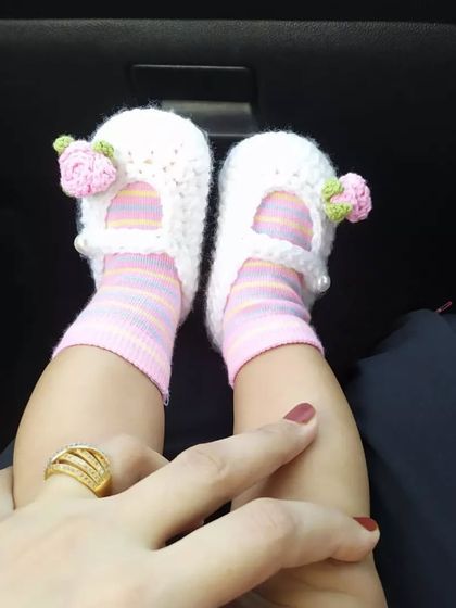 These tiny feet turned one today! She is wearing a pair of my white crochet booties with delicate pink roses, a special accessory for her first birthday.