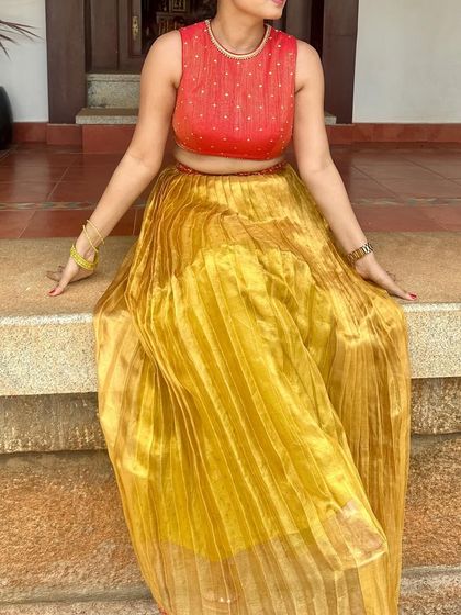 The client seated, showing the flow and shimmer of the mustard yellow pleated skirt.