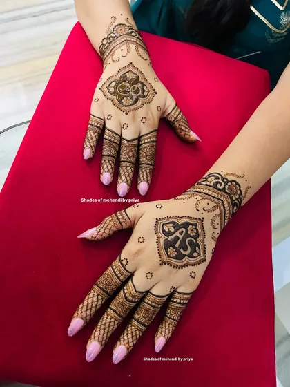 A classic engagement mehendi design. The focus is on a central mandala on the back of the hands, which incorporates the couple's initials 'A' and 'S' in a stylish font.
