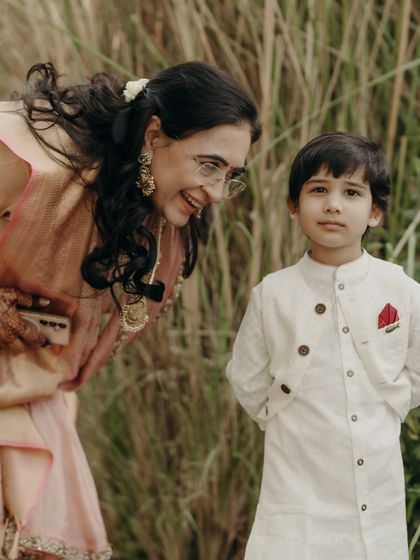 A sweet moment between the mother of the bride and her grandson. Her elegant Kanjeevaram silk saree in a soft peach tone was a key piece in the family's 'shades of sunset' color palette.