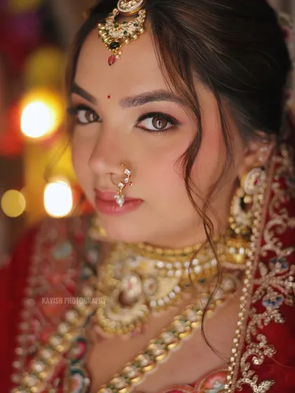 A stunning close-up of a bride, with soft bokeh lights in the background. This portrait focuses on her expressive eyes and intricate bridal jewelry.