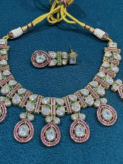 A beautiful kundan necklace set with large teardrop pendants, accented with ruby and emerald colored stones.