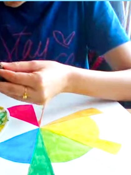 A student learning about the color wheel by painting segments with watercolors, a foundational exercise in color theory.