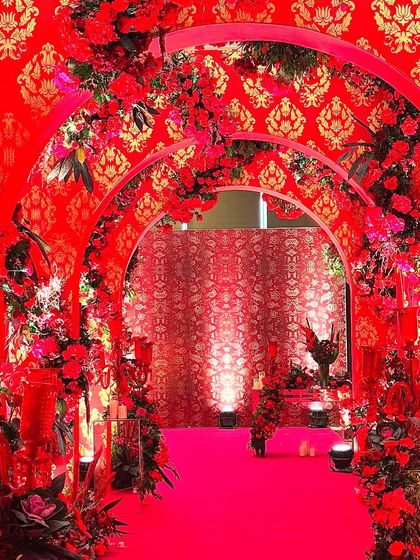 A stunning entrance tunnel with red arches and a red-and-gold patterned wallpaper. The design is a beautiful fusion of modern structure and traditional motifs, creating a grand and welcoming passage for guests.