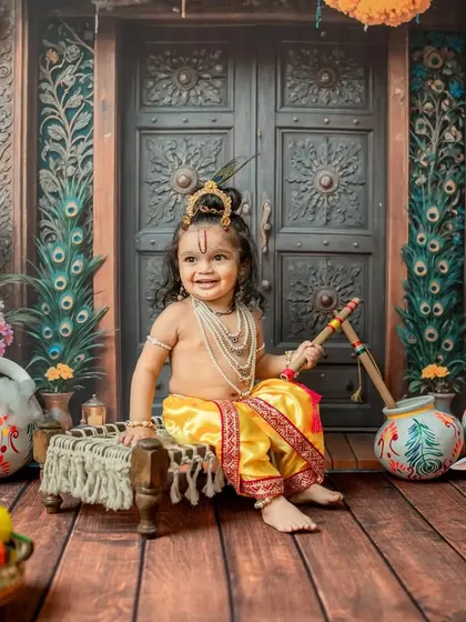 A beautiful smiling portrait of the toddler Krishna on the cot.