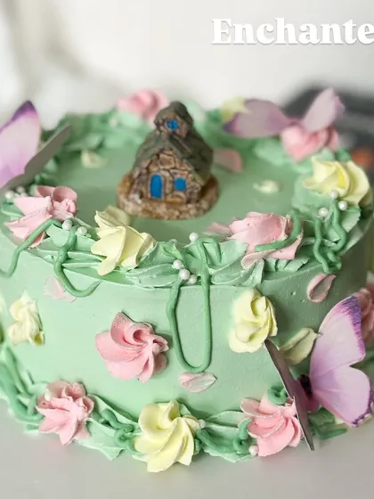 An enchanted forest on a cake. This whimsical design features a tiny house, delicate butterflies, and piped flowers, creating a magical world for a special celebration.
