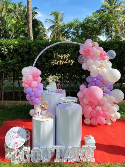 A clear daytime shot of the outdoor lawn party, showcasing the vibrant pastel colors of the balloons against the green grass and blue sky.