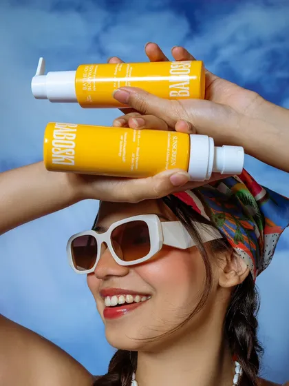 A creative product-in-use shot for a sunscreen brand. The composition is playful and graphically interesting, clearly showcasing the product while maintaining a strong lifestyle feel.