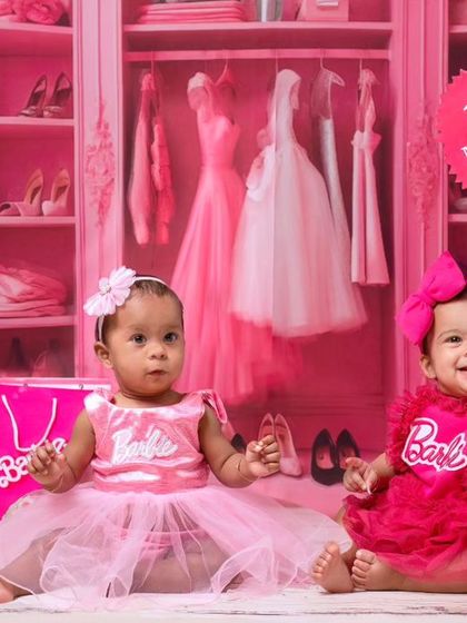 Double the fun with twin baby girls dressed as Barbie. This shot captures their adorable interaction in the fully pink, sparkly studio setup.