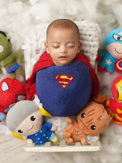 This little Superman is surrounded by his superhero friends. This is a fun and popular theme for parents who are fans of comics and movies.