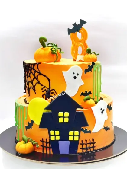 A spooky and fun Halloween-themed cake made for a birthday celebration. This two-tiered chocolate truffle cake features edible ghosts, pumpkins, bats, and a haunted house.