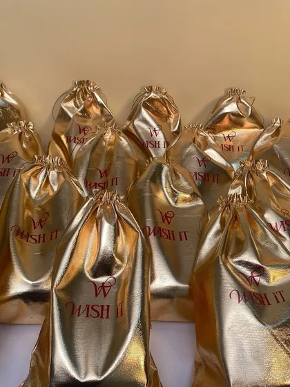 More of our golden potli bags, shining and ready to go. The custom "Wish It" branding adds a personal touch to these elegant favors.