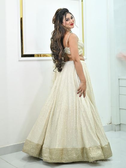 A back view of the ivory and gold lehenga, highlighting the simple yet elegant design and the model's long, flowing hair.