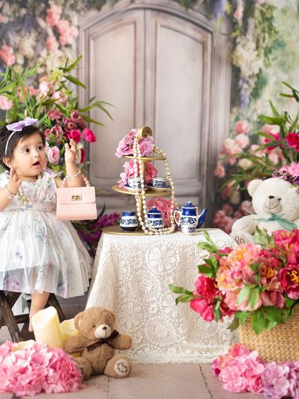 A little fashionista with her pink purse at a floral tea party. My studio is filled with props to spark imagination and create playful portraits.