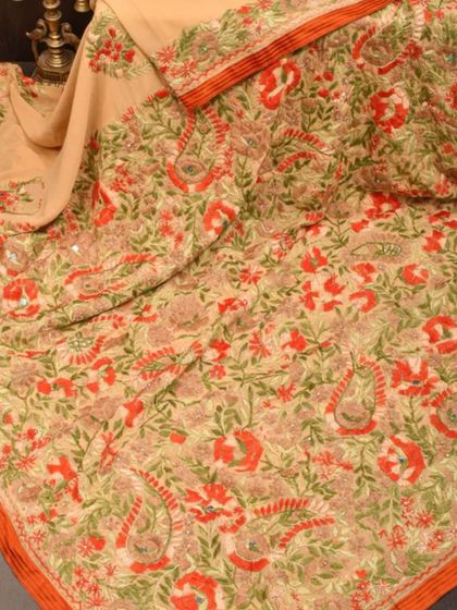 A beautiful cream-colored saree with intricate floral embroidery in shades of orange and green. This is a delicate and artistic piece.
