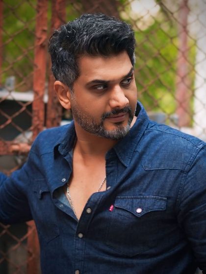 Actor Ali Hasan styled with a classic salt-and-pepper look. The haircut is sharp and symmetrical, enhancing his features for a strong, masculine portrait.