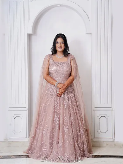 A full-length portrait of the bride in her beautiful pastel gown, posing elegantly against a white arched wall.