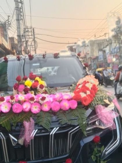 A close-up of the floral arrangement on a Mahindra XUV, showing the detail of the pink and yellow flowers combined with fresh green ferns.