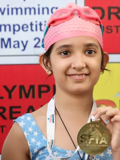 The smile of a champion. This young swimmer proudly displays her gold medal at the Future Champions Swimming Competition. These moments are built on effort, growth, and showing up when it counts.