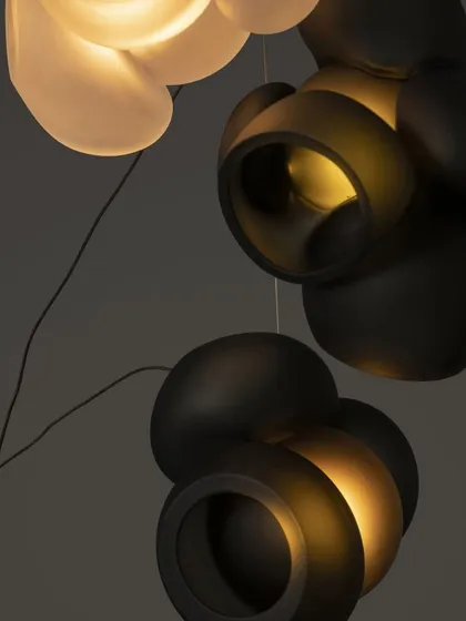 A close-up detail of the Bocci 100 series, showing the contrast between the matte black and translucent white glass. Each pendant is a unique result of the glassblowing process.