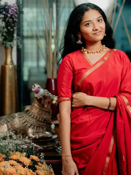 A close-up of the client, her simple gold jewelry perfectly complementing the understated elegance of the red saree.