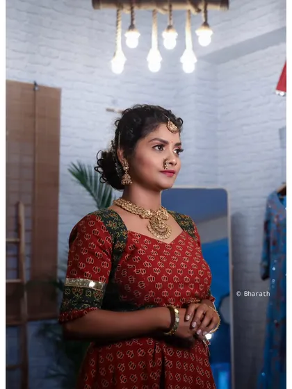 A candid-style shot of the model in a traditional outfit within a decorated room. This image shows how the attire looks in a natural, indoor environment.