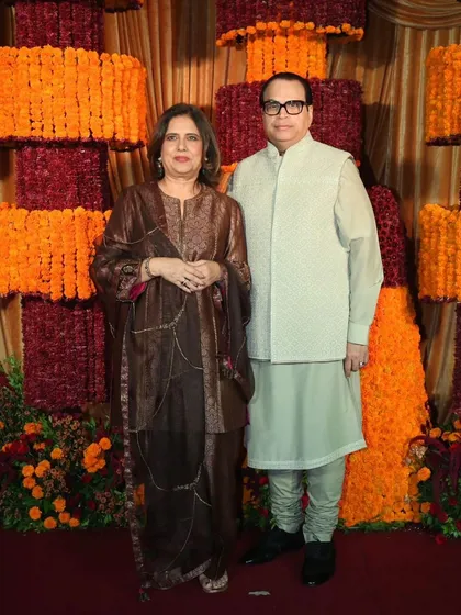 The hosts of a Diwali party posing in front of the spectacular marigold installation.