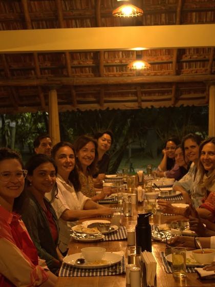 A table of smiling guests from around the world enjoying a meal together. Our communal dining experience fosters friendship and connection, which is also a part of healing.
