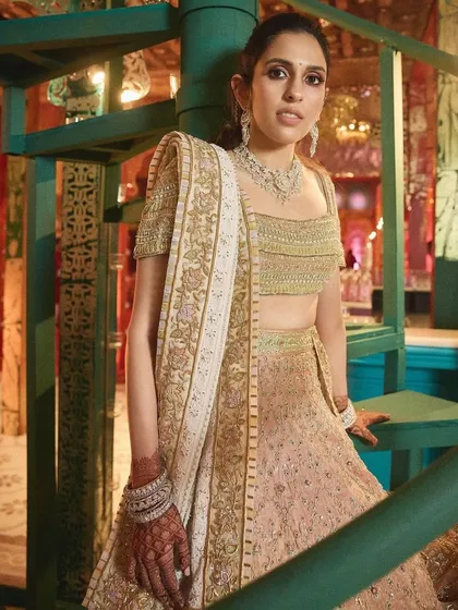 A different angle of the peach lehenga, highlighting its graceful design against a unique, artistic backdrop.