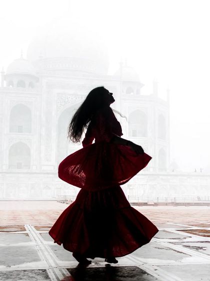 A silhouette of a woman in a flowing red dress against the ethereal, foggy backdrop of the Taj Mahal. This artistic shot combines portraiture with iconic architecture for a timeless feel.