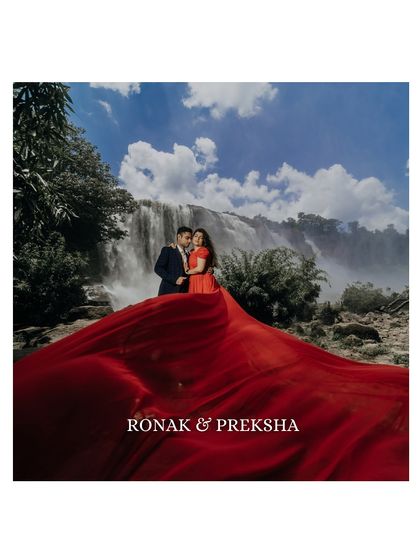 A stunning wide shot of a couple standing before a massive waterfall, with the bride's red dress spread out dramatically. This image showcases our ability to create epic, fairytale-like moments in nature.