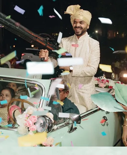 We believe the groom's entry should be just as dramatic as the bride's. Here, the groom makes his grand entrance in a vintage car, firing a confetti gun to kick off the baraat with incredible energy and style.