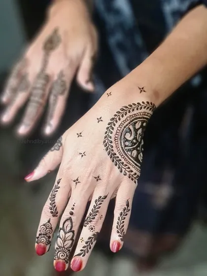 A simple yet striking half-mandala on the back of the hand, paired with leafy vines on the fingers.