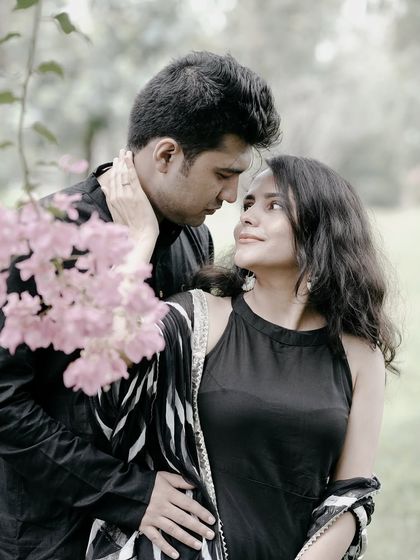 A classic romantic pose, with the couple looking into each other's eyes, surrounded by soft pink flowers.
