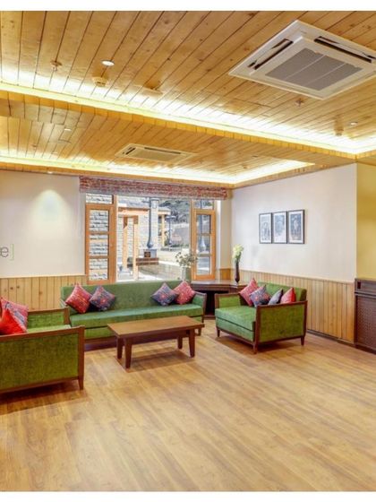 The lounge area at the Janjehli Resort lobby is designed to feel warm and inviting. We used wood-paneled ceilings and walls, comfortable green sofas, and custom-printed cushions inspired by local flora and fauna.