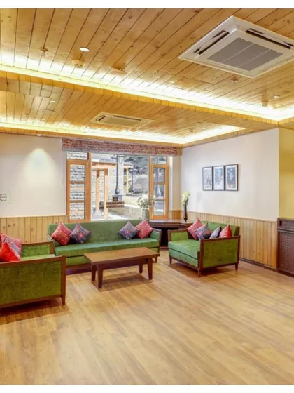 The lounge area at the Janjehli Resort lobby is designed to feel warm and inviting. We used wood-paneled ceilings and walls, comfortable green sofas, and custom-printed cushions inspired by local flora and fauna.