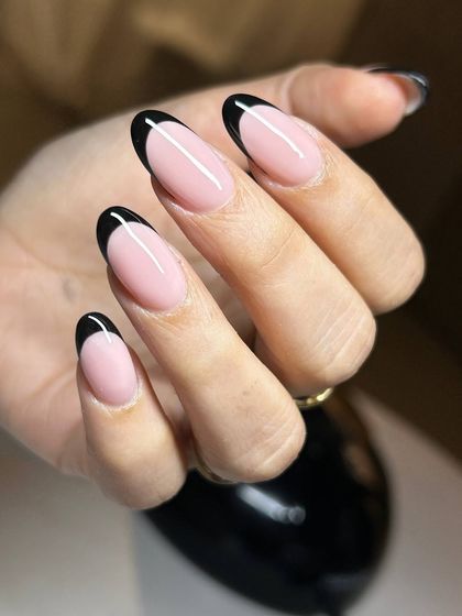 A bold and striking French manicure with black tips on long, almond-shaped nails. This edgy twist on a classic design is modern and sophisticated.