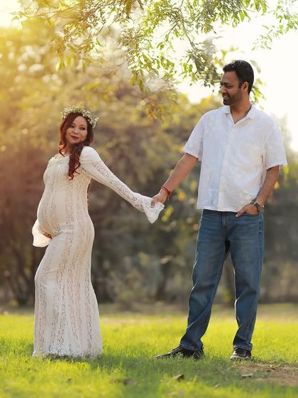 A romantic walk in the park, with the mother-to-be in a lovely white lace gown. The golden hour lighting creates a soft and dreamy feel.