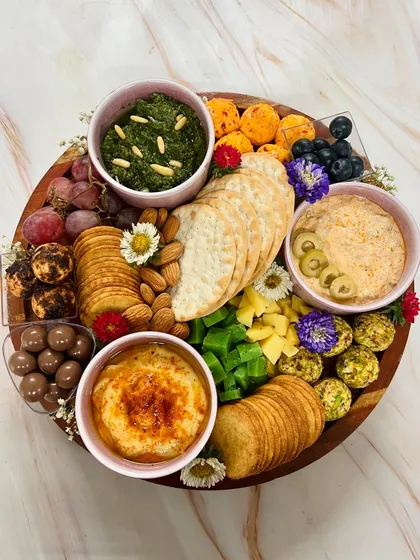 Our cheese and dips platters are perfect for any get-together. This one is overflowing with artisanal cheese balls, creamy dips like our signature pesto and baked brie, assorted crackers, nuts, and fresh fruit. It's a feast for the eyes and the palate.