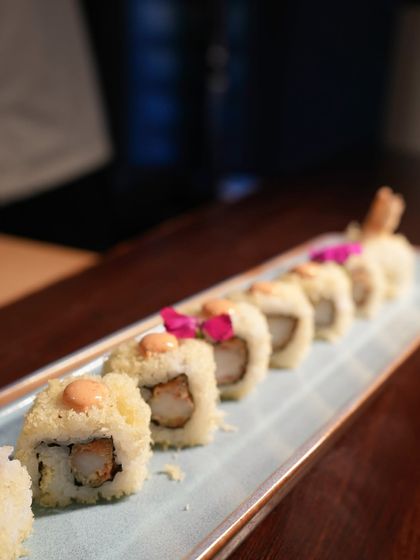 This is our Ebi Tempura Roll, filled with crispy fried prawn and topped with tempura flakes and a dot of spicy mayo. It's a delightful combination of crunchy, savory, and creamy textures.