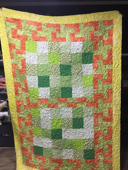 A full view of the cheerful green and orange quilt.