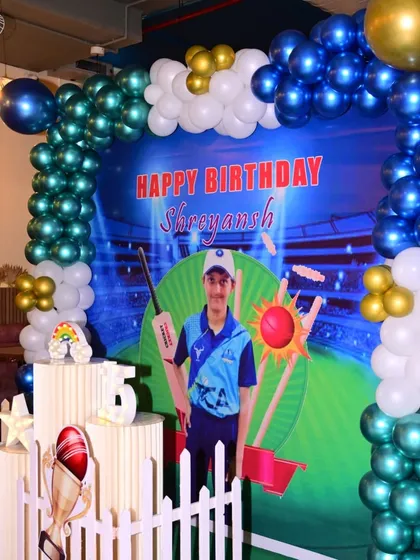 For young sports fans, I offer themed decorations like this cricket party. It includes a custom backdrop featuring the birthday boy, a balloon arch in team colors, and cricket-themed props.