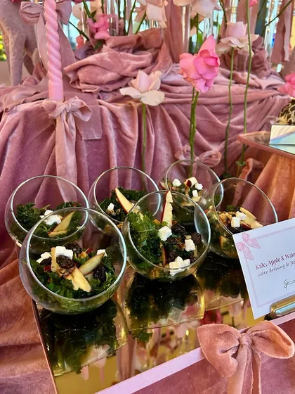 The salad course, featuring a Kale, Apple & Walnut Salad, served in individual glass bowls on a pink velvet-draped table.