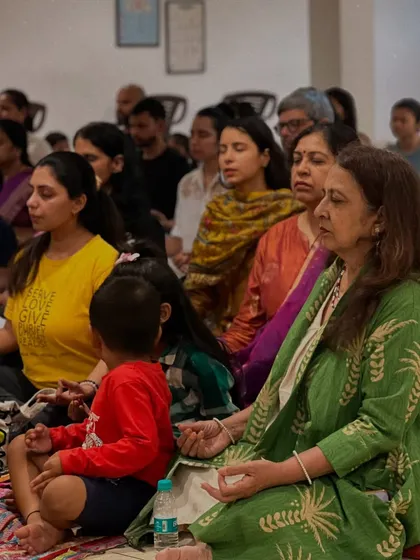 Participants of all ages, including a young child, sit together in meditation. It is a beautiful reminder that the path to inner peace is open to everyone.