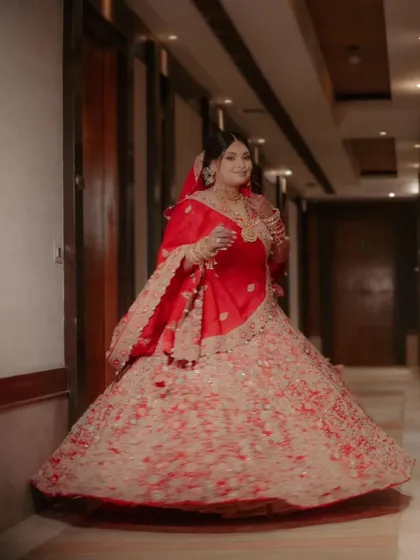 A full-length shot of Shalini, her red and cream lehenga twirling, captured in a grand hotel corridor.